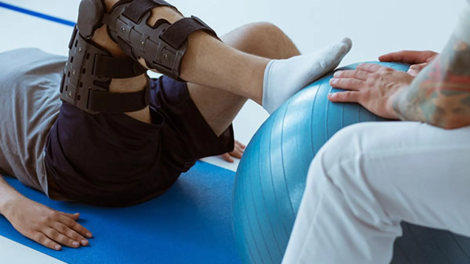 Patient in knee brace performing rehabilitation exercise with stability ball during physical therapy session at Salisbury clinic.